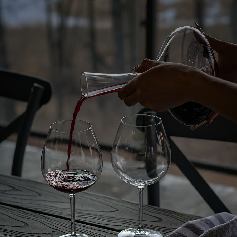 Red wine being poured into a glass from a decanter